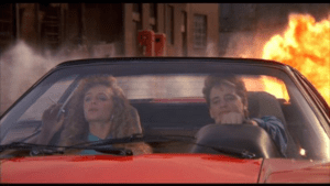 Two women in a red car with smoke coming from the window.