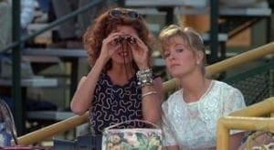 Two women looking through binoculars at a table.