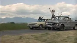 Two people are jumping in the air from a truck.