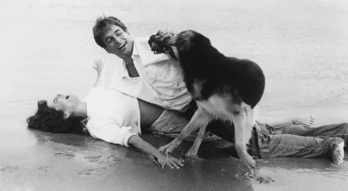 A man and his dog are playing in the sand.