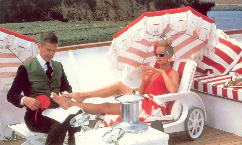 A man and woman sitting on chairs under an umbrella.