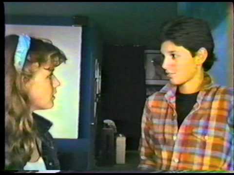 A young man and woman talking in front of a mirror.