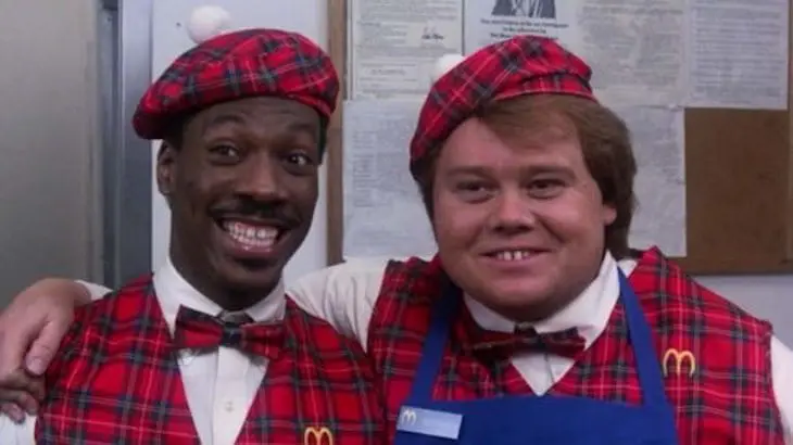 Two men in red plaid vests and ties.