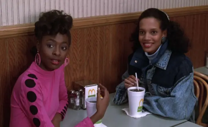 Two girls sitting at a table with drinks.