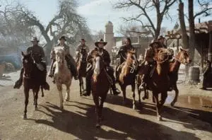 A group of men riding horses down the street.