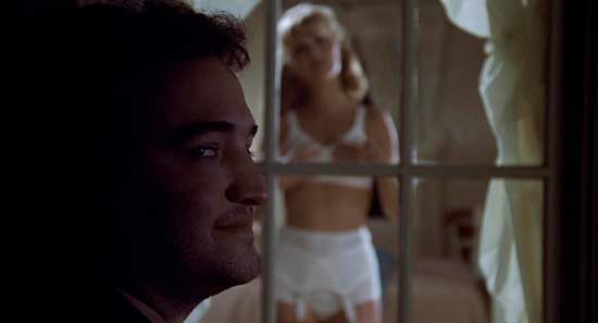 A man and woman in white underwear looking out of the window.