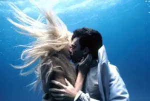 A man and woman kissing underwater in the ocean.