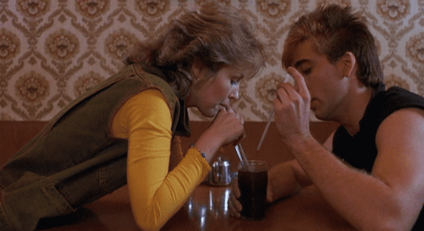 A man and woman sitting at a table with drinks.