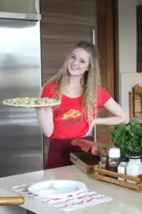 A woman holding a pizza on top of a pan.