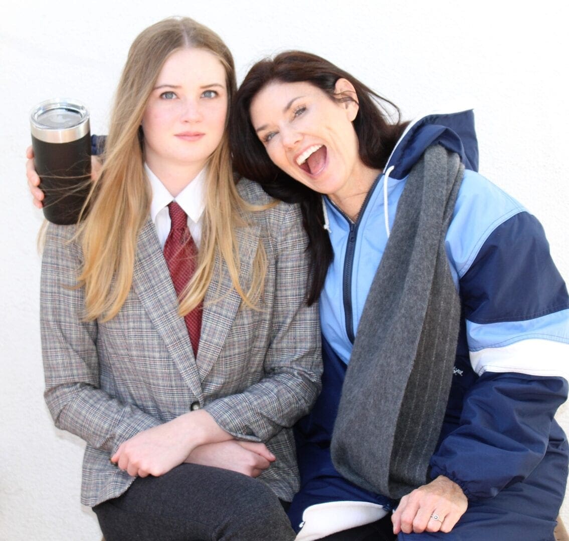 Two women posing for a picture with a drink.