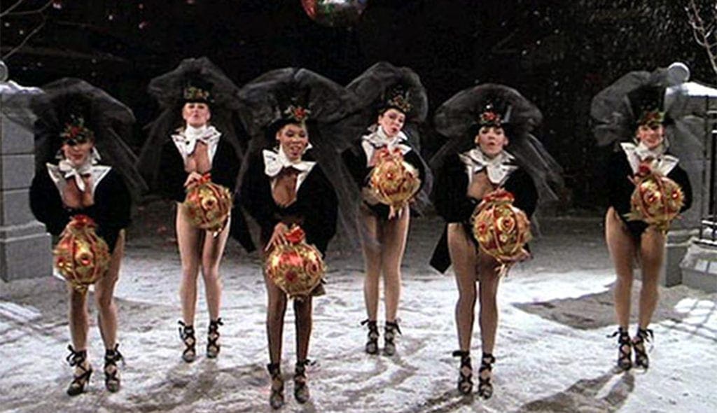 A group of women in costumes holding umbrellas.