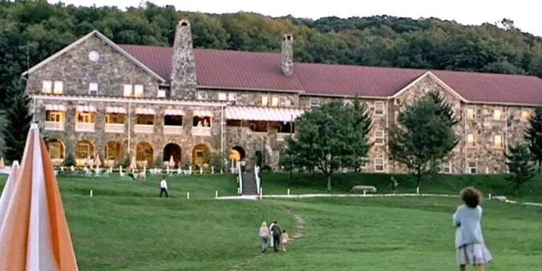 A large building with people walking around in the grass.