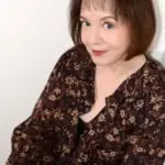 A woman in brown and black shirt sitting down.