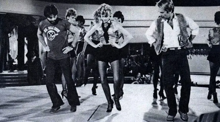 A group of people dancing in the middle of an indoor dance floor.