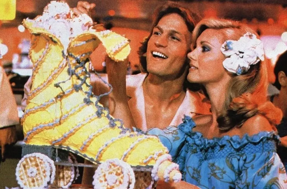 A man and woman are looking at some cakes.