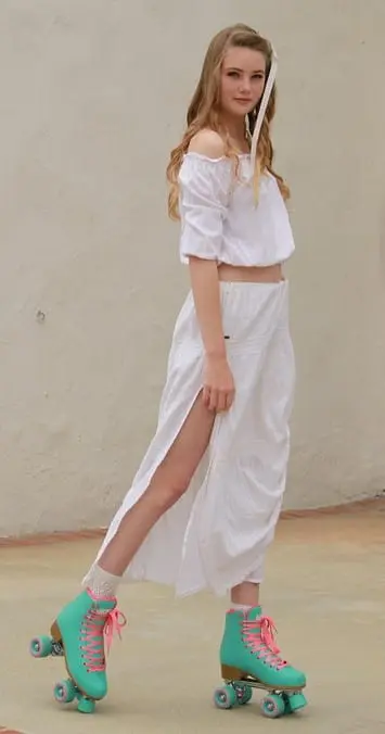 A woman in white dress standing on the sidewalk.