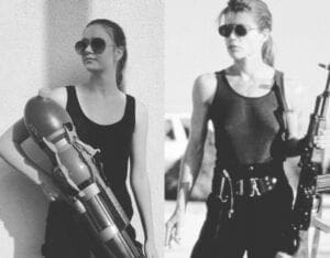 Two women in black shirts and sunglasses holding a gun.