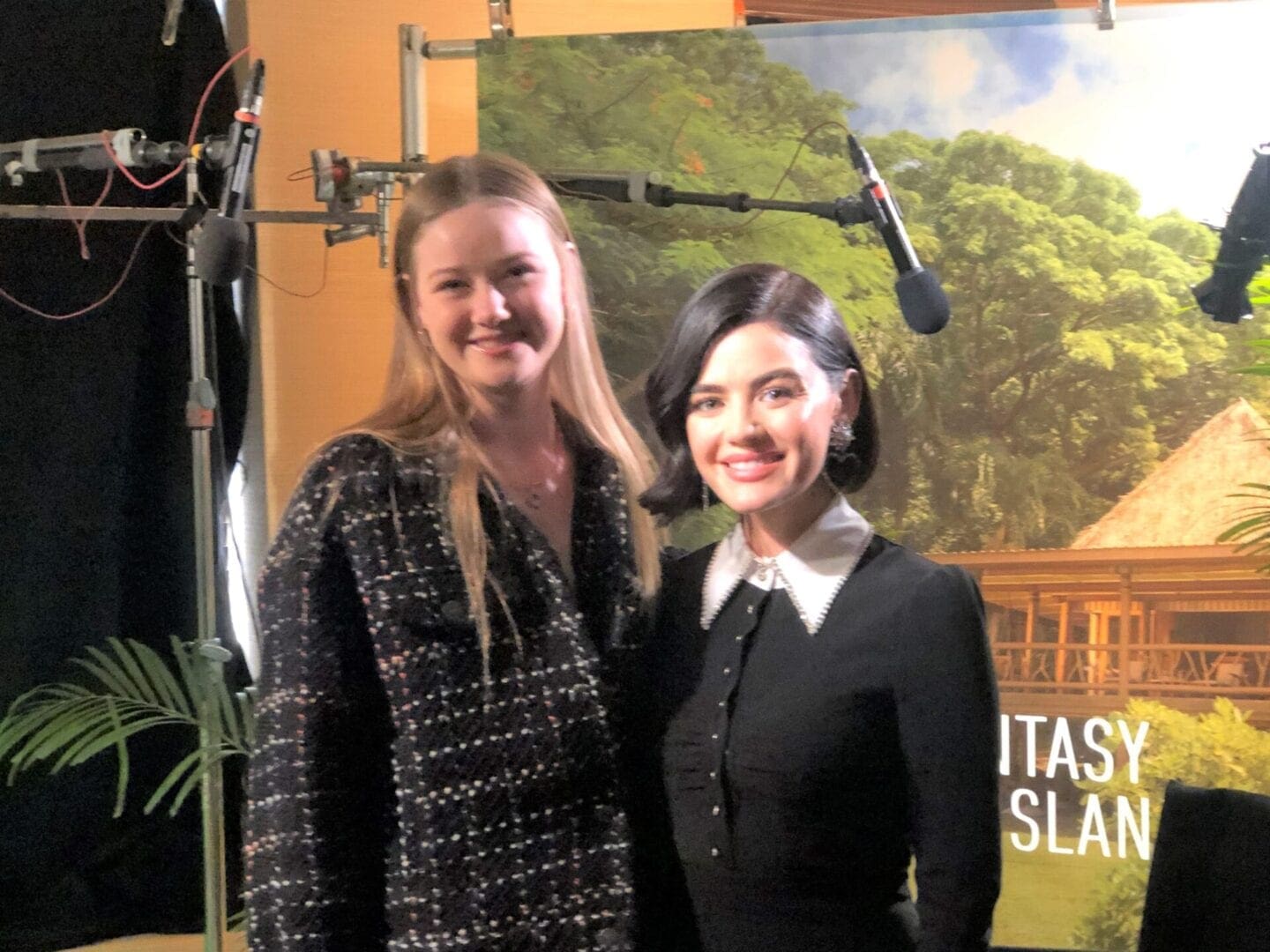 Two women standing next to each other in front of a poster.