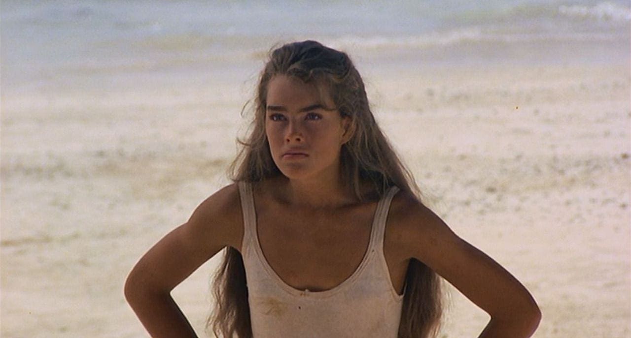 A woman with long hair standing on the beach.