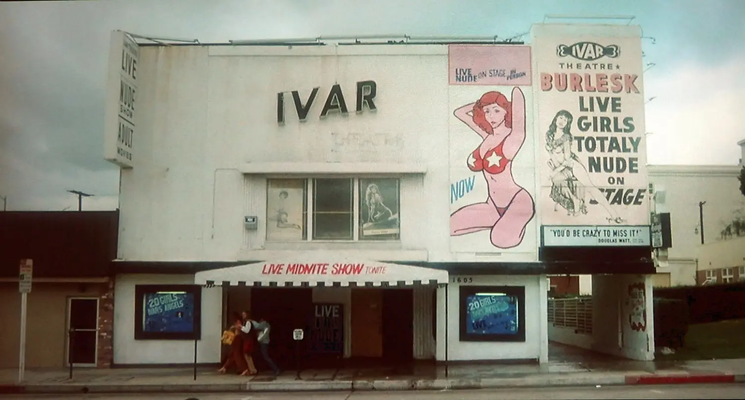 A building with a woman sitting on the side of it.