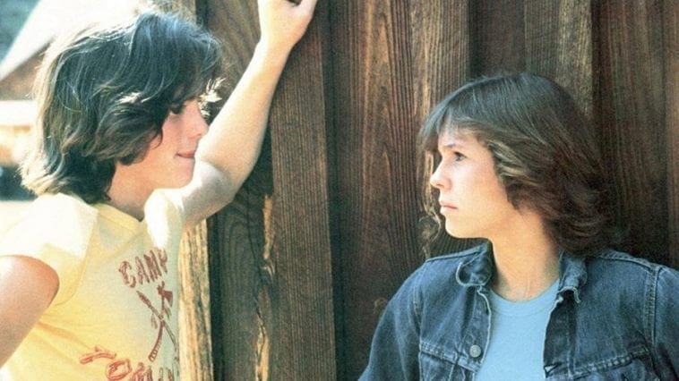 Two people standing next to each other near a wooden wall.