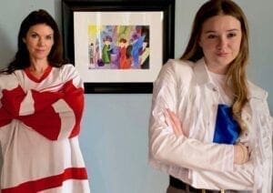 Two women standing next to each other in front of a painting.