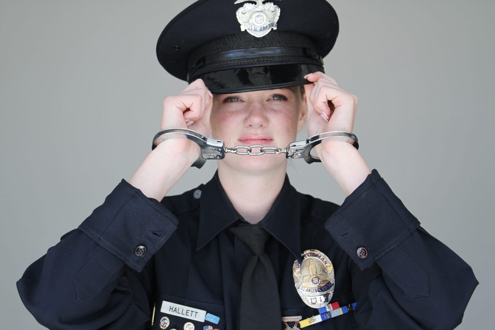 A woman in police uniform holding onto handcuffs.