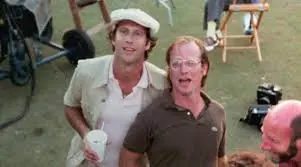 Two men in golf clothes on golf course.