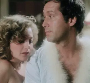 A man and woman in white fur coats looking at each other.