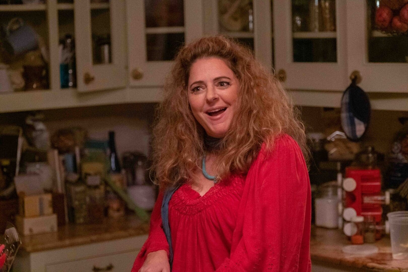 A woman in red shirt standing next to a kitchen.